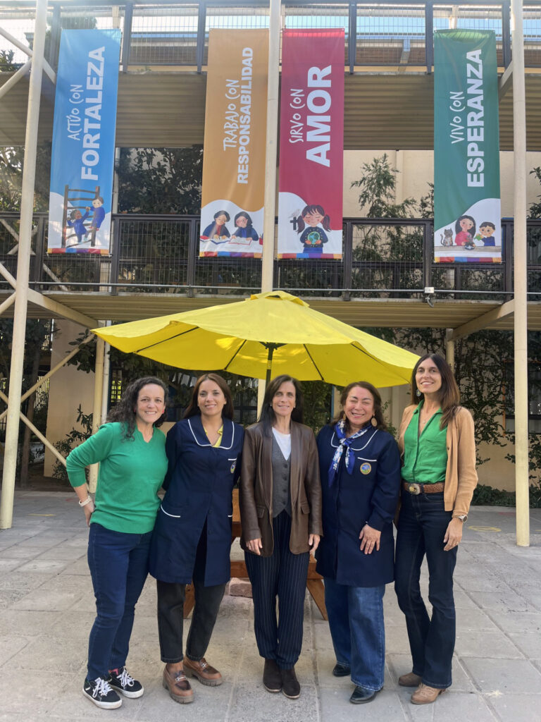 Grupo de personas frente a un establecimiento educacional.