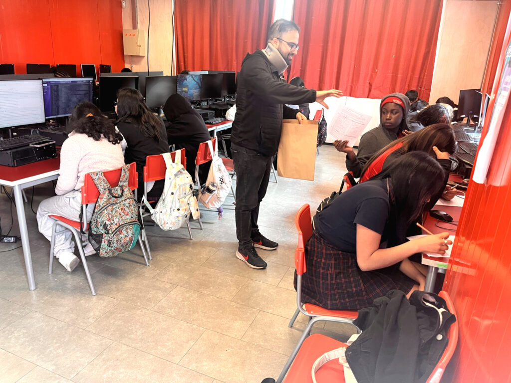Adulto acompaña a estudiantes durante una actividad en aula.